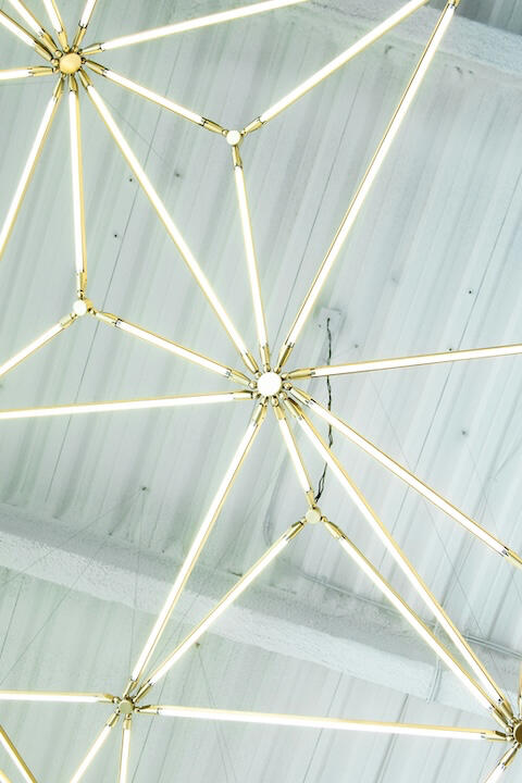 Eine Lichtinstallation hängt an der Decke. Sie sieht aus wie ein Spinnennetz.